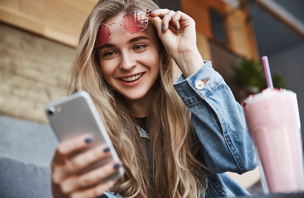 Retrato de primer plano de mujer feliz sentada en la cafetería, sungl de despegue