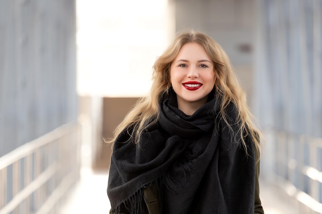 Retrato de primer plano de una mujer joven feliz sonriendo Mujer de retrato de moda elegante Posando en la ciudad Hermosa chica en otoño abrigo verde y bufanda negra posa en un paso de peatones elevado