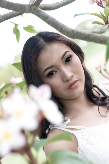 Foto retrato en primer plano de una mujer joven junto a flores en flor