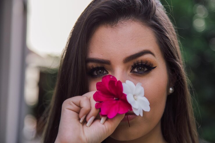 Retrato en primer plano de una mujer joven oliendo flores