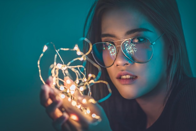 Retrato en primer plano de una mujer joven que sostiene una luz de cuerda iluminada