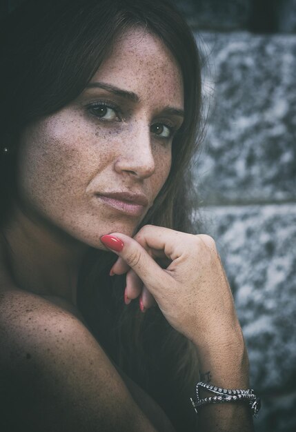 Foto retrato en primer plano de una mujer de pie junto a una pared de piedra