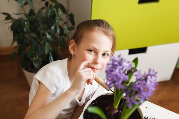 Retrato de primer plano de una niña feliz y linda cuidando las plantas caseras