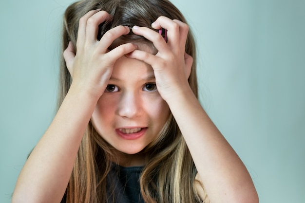 Retrato de primer plano de niña infeliz sorprendida con el pelo largo con la cabeza en las manos.