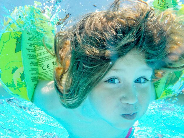 Foto retrato en primer plano de una niña nadando bajo el mar