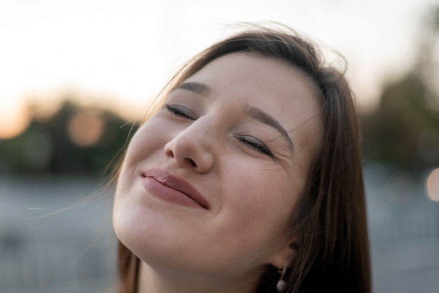 Retrato de primer plano de niña sonriente. Feliz sonrisa sincera. Mujer joven contenta en la calle.