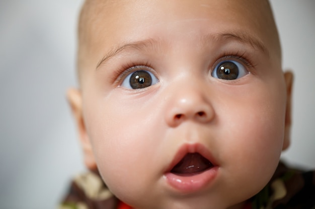 Retrato de primer plano de un niño de 8 meses de edad y está sonriendo. Vestido con traje militar