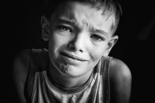 Retrato en primer plano de un niño haciendo la cara contra un fondo negro