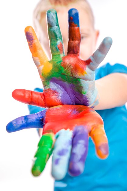 Retrato en primer plano de un niño con manos coloridas contra un fondo blanco