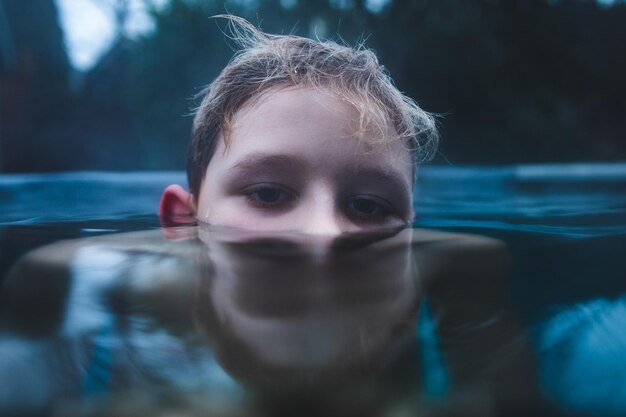 Retrato en primer plano de un niño nadando en un lago