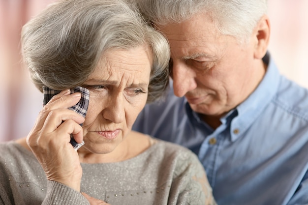 Retrato de primer plano de una pareja de ancianos triste sobre fondo de color