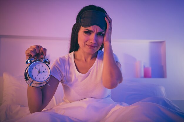 Retrato de primer plano de preocupada mujer triste enferma que sufre dolor de cabeza sentado en la cama