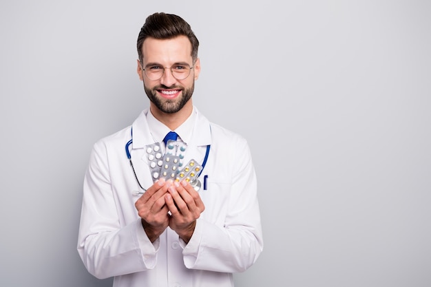 Retrato de primer plano de su médico profesional calificado agradable atractivo alegre alegre alegre sosteniendo en las manos placas de solución de terapia de tabletas aislado en color pastel gris blanco claro