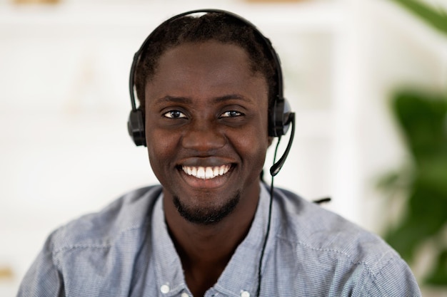 Retrato de primer plano de trabajador de centro de llamadas de gerente de línea directa de hombre negro en auriculares