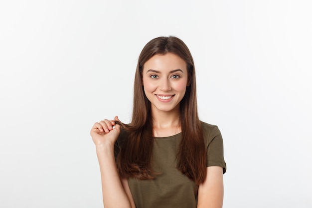 Retrato del primer del retrato casual de la mujer de Yong en la opinión positiva, sonrisa grande, modelo hermoso que presenta en estudio sobre la pared blanca.