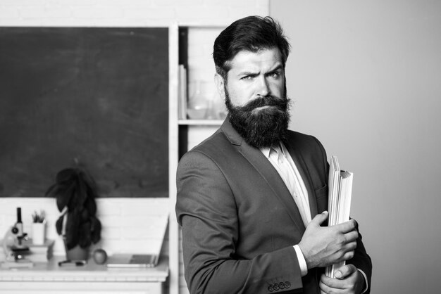 Retrato de profesor en el aula guapo hombre barbudo cerca de la pizarra en el profesor de aula profesor