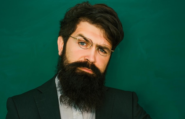 Retrato de profesor barbudo en la lección de la escuela en escritorios en el aula cerca del profesor en clase en