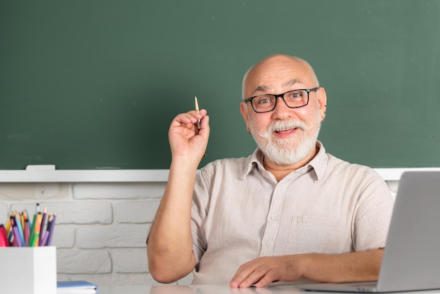 Retrato de profesor maduro o profesor tutor trabajando en la mesa en la universidad o la escuela