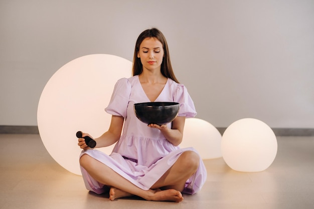 Retrato de una profesora de yoga tocando un cuenco tibetano o cantando una campana en el gimnasio durante un retiro de yoga