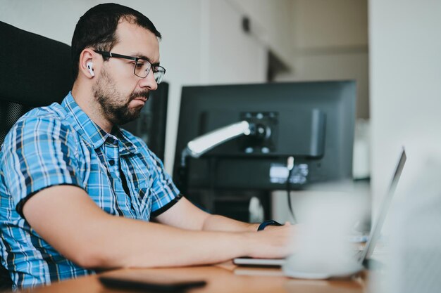 Retrato de un programador profesional que trabaja concentrado en computadoras en diversas oficinas. Desarrollo de tecnologías de TI modernas de aplicaciones de programas de inteligencia artificial y concepto de videojuegos.