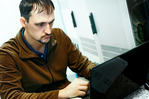 Retrato de un programador en el trabajo Una escena auténtica Un especialista en TI ha estado trabajando en una computadora portátil en la sala de servidores