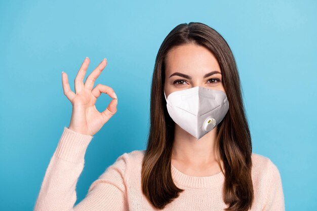 El retrato del promotor de la muchacha alegre positiva muestra la máscara del desgaste del signo bien aislada sobre el fondo de color azul pastel