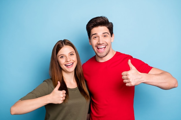 Retrato de promotores de dos cónyuges románticos muestran el pulgar hacia arriba firmar decidir anuncios elegir asesoramiento promocional ventas usar camiseta roja verde aislada sobre fondo de color azul