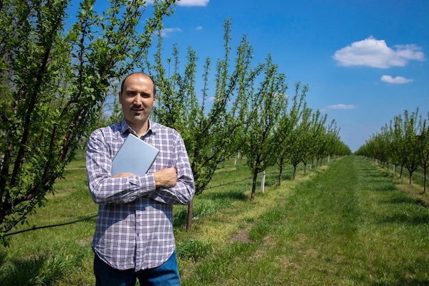 Retrato del propietario de una plantación de hombre con pie de tableta en su huerto.