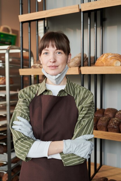 Retrato de propietario en uniforme mirando a la cámara mientras está de pie en la panadería