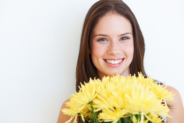 Retrato de ramo de flores y mujer de estudio feliz con producto floral regalo sostenible o regalo de primavera amarillo Mockup cara espacio publicitario y chica modelo ecológica aislada sobre fondo blanco