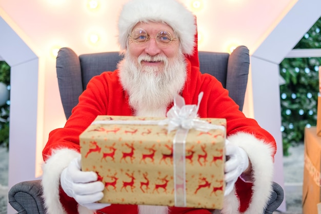 Foto retrato real autêntico papai noel com presentes de natal nas mãos sentado no shopping center