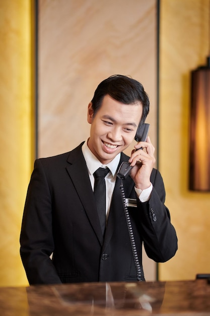 Retrato de la recepcionista del hotel sonriente respondiendo a una llamada telefónica