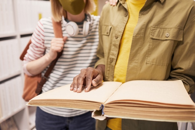 Retrato recortado de estudante ajudando um amigo cego no espaço de cópia da biblioteca