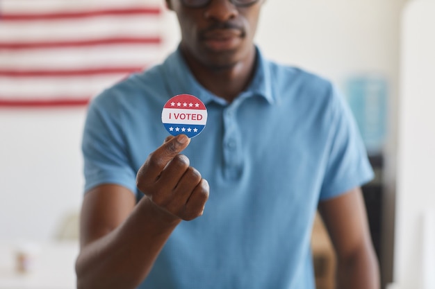 Retrato recortado del hombre africano moderno sosteniendo la pegatina VOTé, espacio de copia