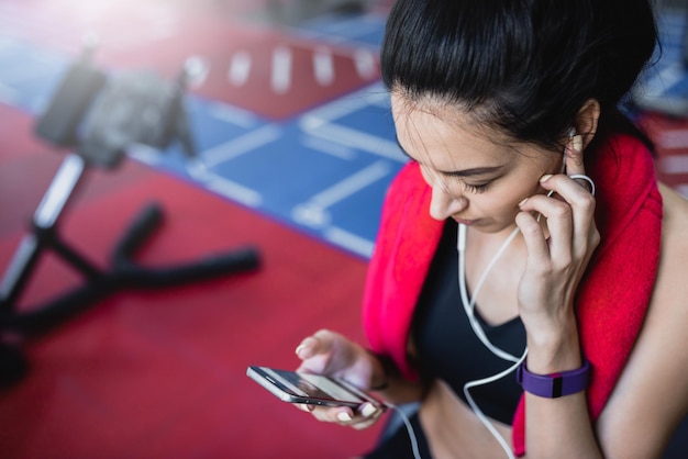 Retrato recortado superior de una hermosa joven deportiva escuchando música desde su teléfono inteligente tomando un descanso después de hacer ejercicio en el gimnasio Concepto de fitness y deporte de tecnología de personas