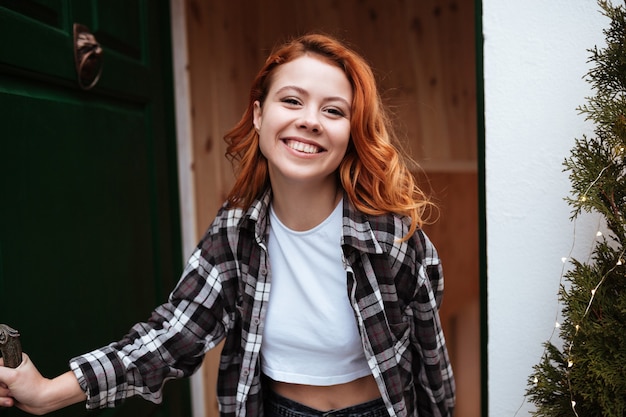 Retrato, de, reír, mujer joven, con, pelo rojo, abrir la puerta