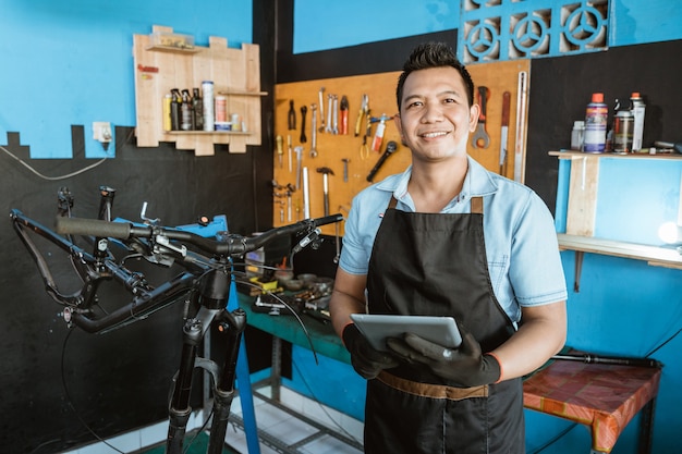 Foto retrato de un reparador sonriente en un delantal como ropa de trabajo con una almohadilla