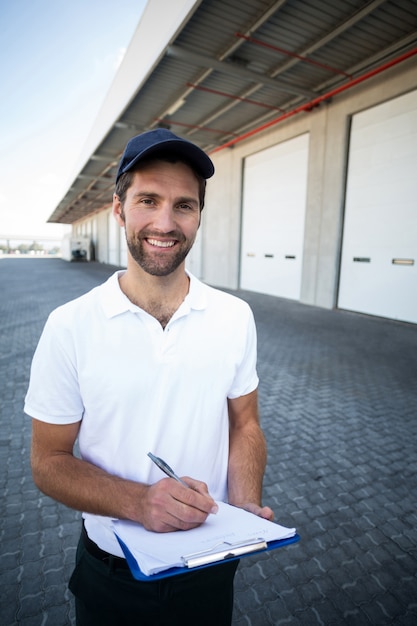 Foto retrato del repartidor está sosteniendo un portapapeles y sonriendo a la cámara