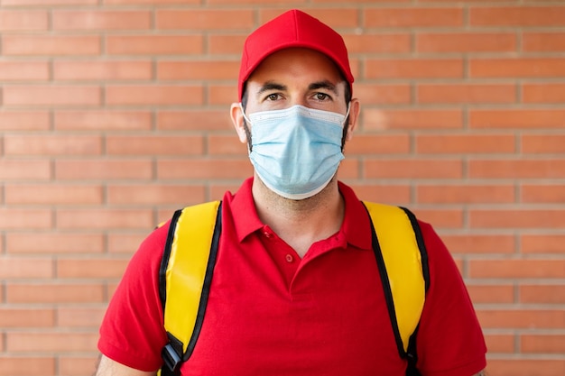 Foto retrato de repartidor en uniforme rojo y mochila térmica de pie al aire libre concepto de servicios para pequeñas empresas