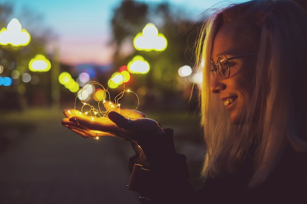 Retrato romântico de uma menina com luzes na rua da noite