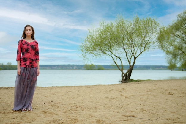 Retrato romântico do estilo de vida de uma mulher sonhadora na praia em um dia ventoso