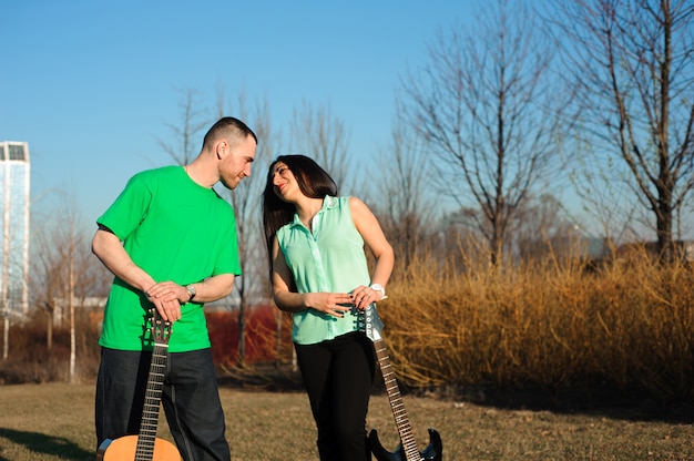 Retrato romántico joven pareja tocando la guitarra bajo un cielo azul