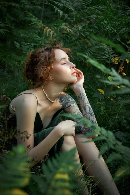 Retrato romántico de una mujer en un helecho en el bosque. Maquillaje natural de mujer de arte descansando en la naturaleza. Matorrales de helechos verdes