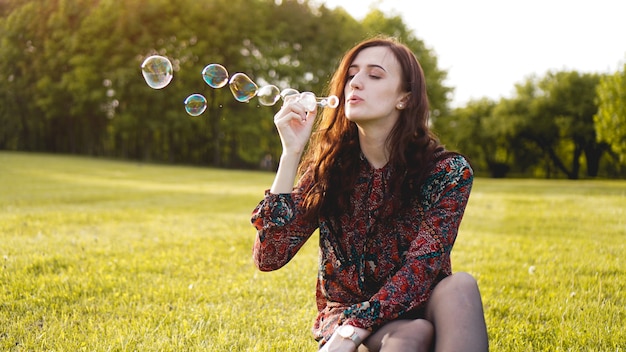 Retrato romántico de mujer joven con globos de jabón. Sunny Valley en un día de verano