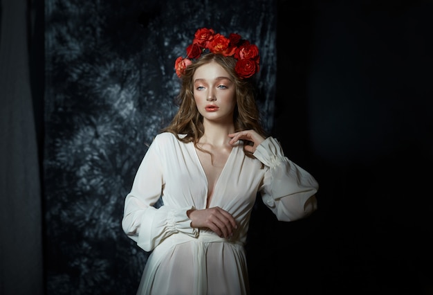 Retrato romántico de primavera de una joven rubia con una corona de flores rosas rojas