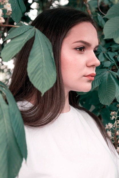 El retrato de la ropa casual de la muchacha atractiva joven en el fondo del árbol de castaña se va. Concepto de juventud, estilo de vida, belleza natural.