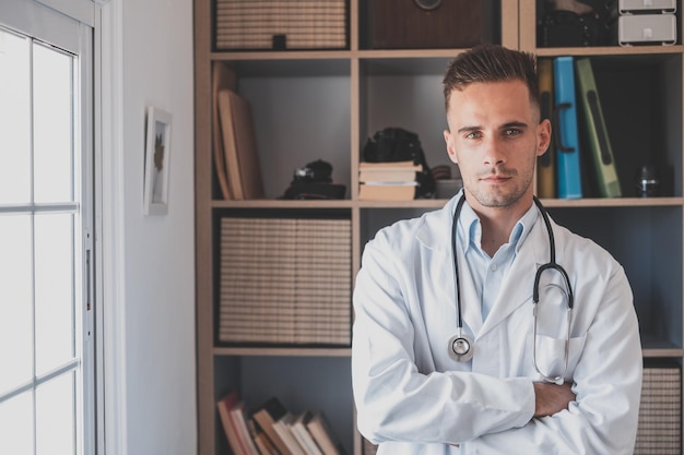 Foto retrato de rostro de un joven médico general sonriente o médico con uniforme médico blanco y gafas mirando a la cámara posando en el hospital hombre blanco feliz médico muestra habilidades de confianza en el lugar de trabajo de la clínicaxa