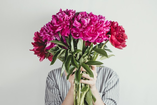 Retrato sin rostro de mujer con ramo de flores violetas y púrpuras