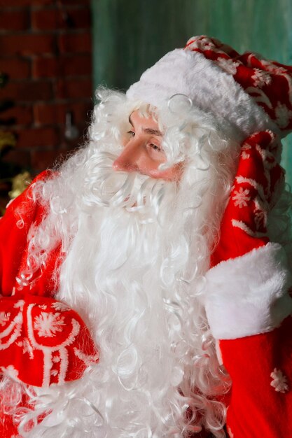 Retrato de un Santa Claus emocional con bolsa de regalos junto a la chimenea de Navidad en salón decorado con árbol de Navidad. Santa Claus viene y trae regalos por la noche. Copie el espacio para el sitio