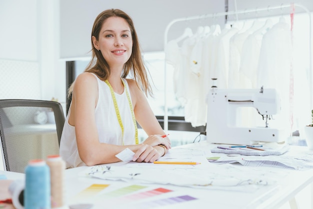 Retrato sastre modista diseñadora de ropa de moda profesional mujer trabajadora adulta feliz sonriendo en el taller de estudio